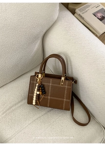 Détail du sac fourre-tout marron rétro avec coutures quadrillées et pompon en bois