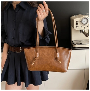 Detail of vintage brown leather tote bag with knotted shoulder straps and embossed logo