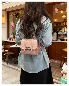 Detail view of a pink butterfly backpack with silver bow buckle on model in soft lighting