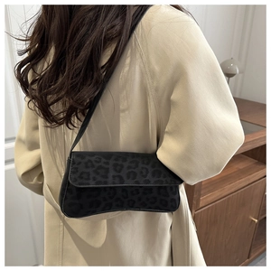 Detail view of the black leopard print shoulder bag worn with a stylish trench coat