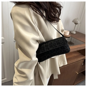 Detail of black leopard print shoulder bag with plush texture on a female model