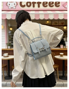 Detail of light blue mini backpack with silver bow and decorative buckle straps