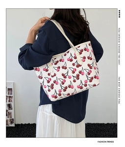 Detail of stylish tote bag featuring cherry prints and shoulder straps for daily use