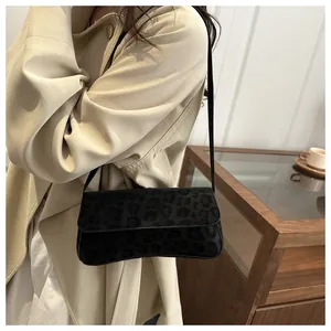 Fashionable black leopard print suede baguette shoulder bag shown on a model