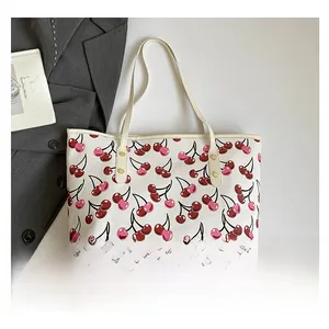 Macro view of cherry print tote bag with gold rivets and leather handles in a chic setting