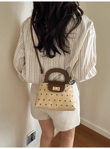 Detail of polka dot quilted crossbody bag with golden metal turn-lock on a model