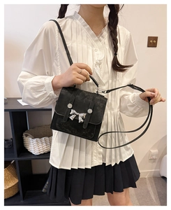 Detail of black mini bucket bag with silver butterfly buckle shown on model