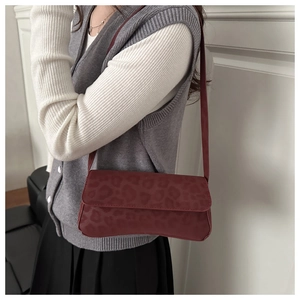 Detail of burgundy baguette bag with leopard embossed texture and sleek shoulder strap