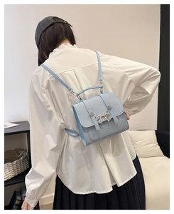 Detail view of light blue mini backpack with silver bow decoration worn by model