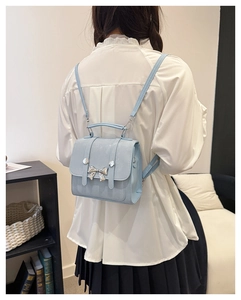 Close-up of mini light blue PU leather backpack with a decorative metal bow and slim straps