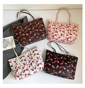 Detail view of large tote bags with cherry prints in four colors on a white background
