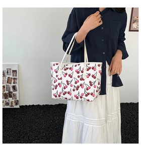 Detail of white tote bag with red cherry print featuring stylish shoulder straps