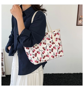 Detailed view of white cherry print tote bag on model showing strap and rivet details