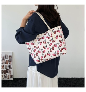 Lifestyle view of white tote bag featuring red cherry prints and slim shoulder straps