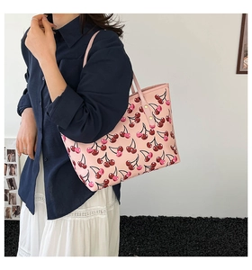 Shoulder strap and rivet detail of pink tote bag with printed cherry pattern