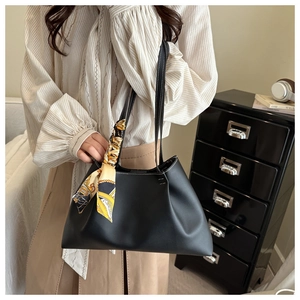 Detail of black PU leather shoulder bag with white contrast stitching and silk scarf
