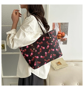 Close-up of a large cherry print tote bag with leather straps on a female model