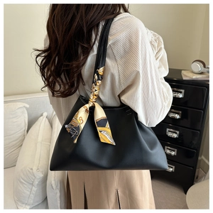 Detail shot of black tote bag featuring a decorative printed scarf on the handle strap