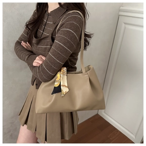 Detail of khaki tote bag with elegant floral silk scarf handle on model shoulder