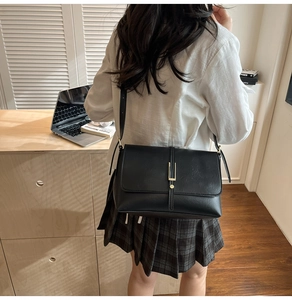 Detail view of a vintage black leather crossbody bag with a gold rectangular metal buckle