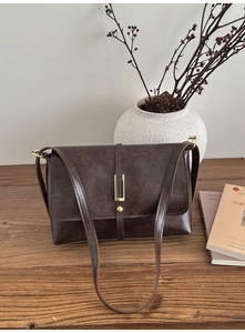 Detail of vintage brown crossbody bag featuring golden buckle and faux leather texture