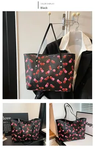 Close-up of black tote bag featuring a vibrant red and pink cherry print pattern