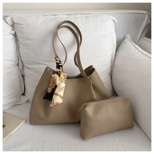 Detail of khaki tote bag with silk scarf handle and matching zipper pouch on white sofa