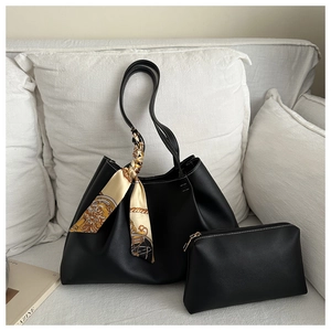 Detail of black leather tote bag with silk scarf on handle and small matching pouch