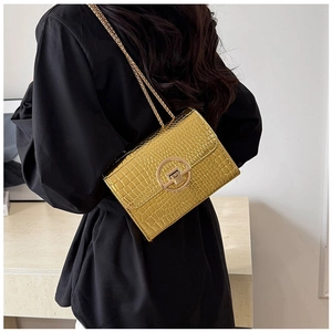 Borsa a spalla dorata con stampa coccodrillo e catena indossata da modella per lo stile