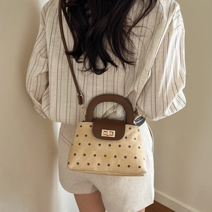 Retro beige polka dot quilted crossbody bag with brown leather handles and gold clasp