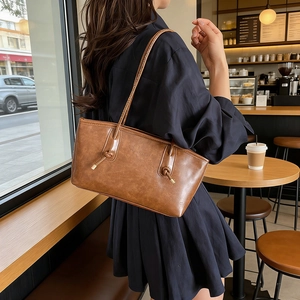Chic retro brown leather tote bag with unique knot straps worn by a model in a cafe