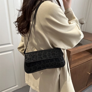 Chic leopard print baguette bag in black and grey, worn on the shoulder by a model