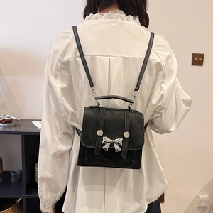 Chic black mini backpack with silver bow accent shown on model in a modern interior