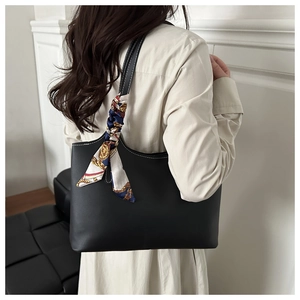 Detail of black leather tote bag with printed silk scarf on handle and contrast stitching