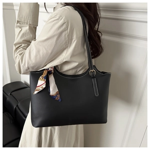 Detail of a black leather tote bag featuring white contrast stitching and silk scarf wrap