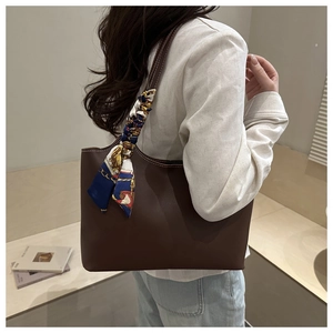 Detail of dark brown tote bag featuring white contrast stitching and decorative silk scarf
