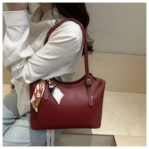 Close-up of burgundy tote bag with a patterned silk scarf tied on the thin shoulder strap
