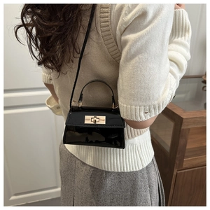 Detailed view of shiny black patent leather mini crossbody bag with gold turn-lock buckle