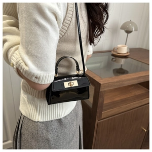 Detail shot of mini black patent leather handbag with gold metal twist lock and top handle