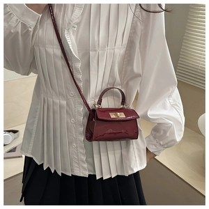 Close-up of a burgundy mini square bag with glossy patent finish and golden twist lock