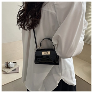 Detail of black glossy patent leather mini bag with elegant gold rectangular twist lock