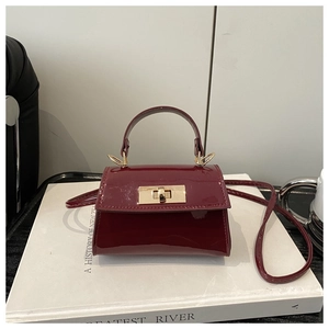 Detailed macro view of wine red patent leather mini crossbody bag with gold buckle clasp