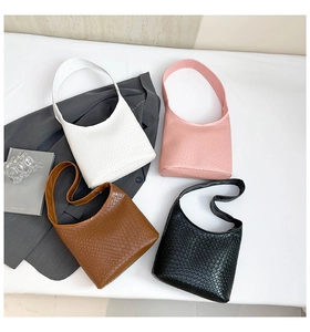 Flat lay of small woven tote bags in white, pink, brown and black with stylish shoulder straps