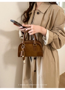 Detailed close-up of a brown retro suede Boston bag with a unique beaded charm accessory