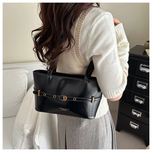 Detailed shot of a black leather underarm bag with gold buckle on a shoulder strap