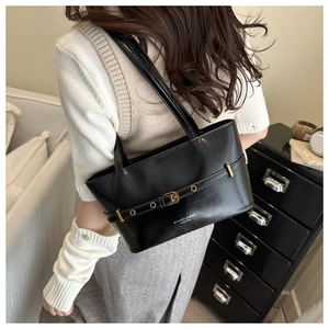 Detail of black faux leather underarm bag with gold buckle and fashion text logo