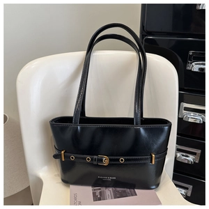 Detail of glossy black leather tote bag featuring a gold buckle and elegant logo branding