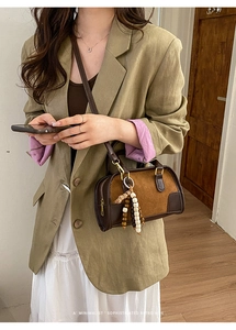 Detail of retro brown leather Boston bag featuring wooden bead charm and shoulder strap