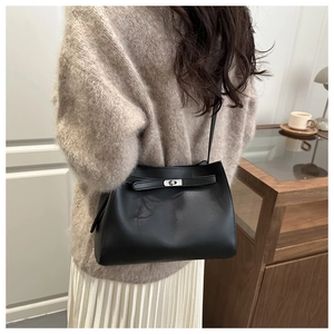 Vista trasera de modelo con bolso de hombro en cuero negro mate y hebilla de plata