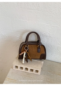 Detail of retro mini Boston bag in brown suede with leather trim and beaded charm